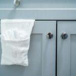 Biały ręcznik na drzwiach nowoczesnej szarej szafki łazienkowej