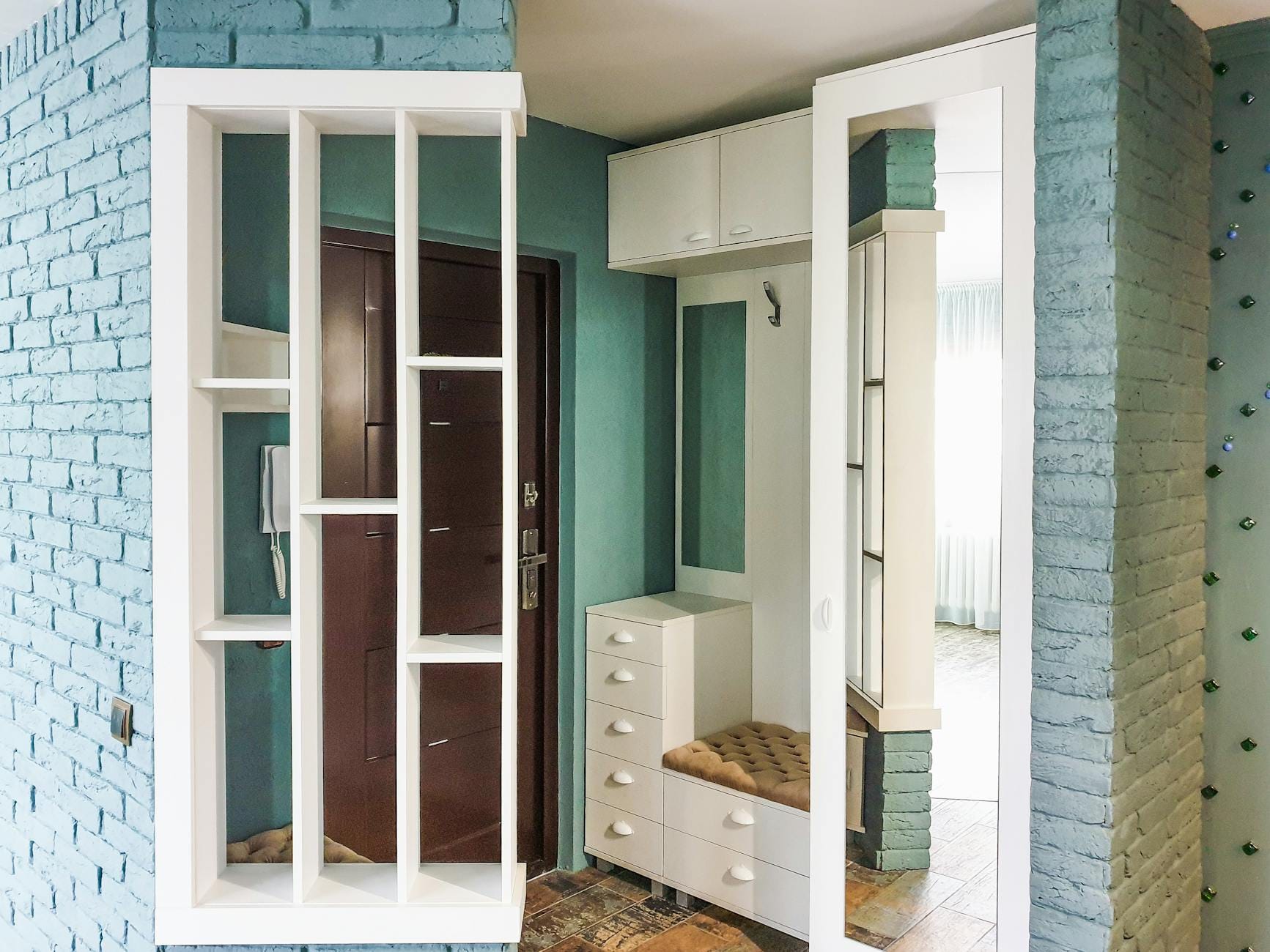 Nowoczesny przedpokój z białą zabudową i ceglaną ścianą