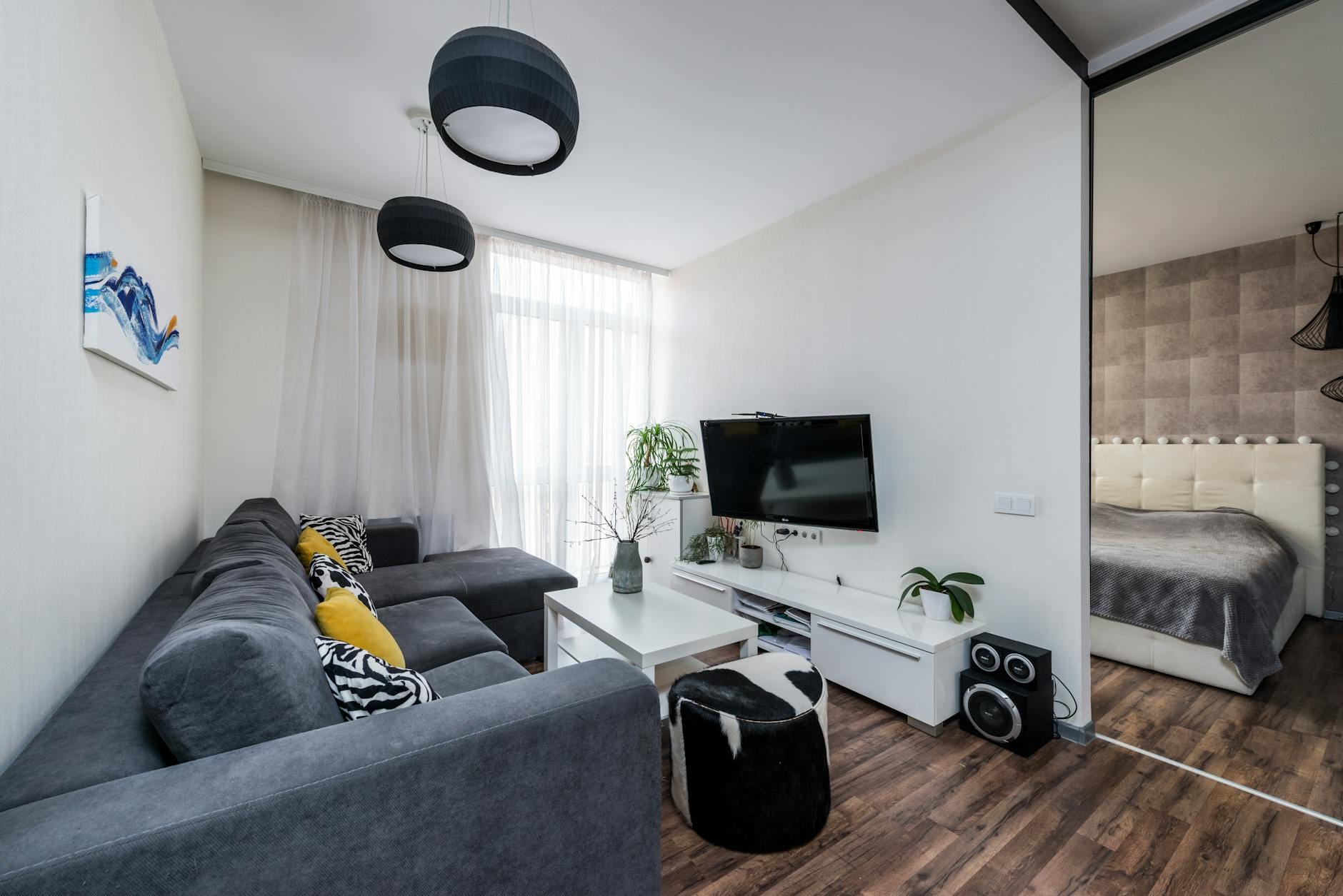Meble do salonu w domu szeregowym jak ujarzmić długie wąskie pomieszczenie Jasny wąski salon w szeregowcu z szarą sofą i roślinami w donicach