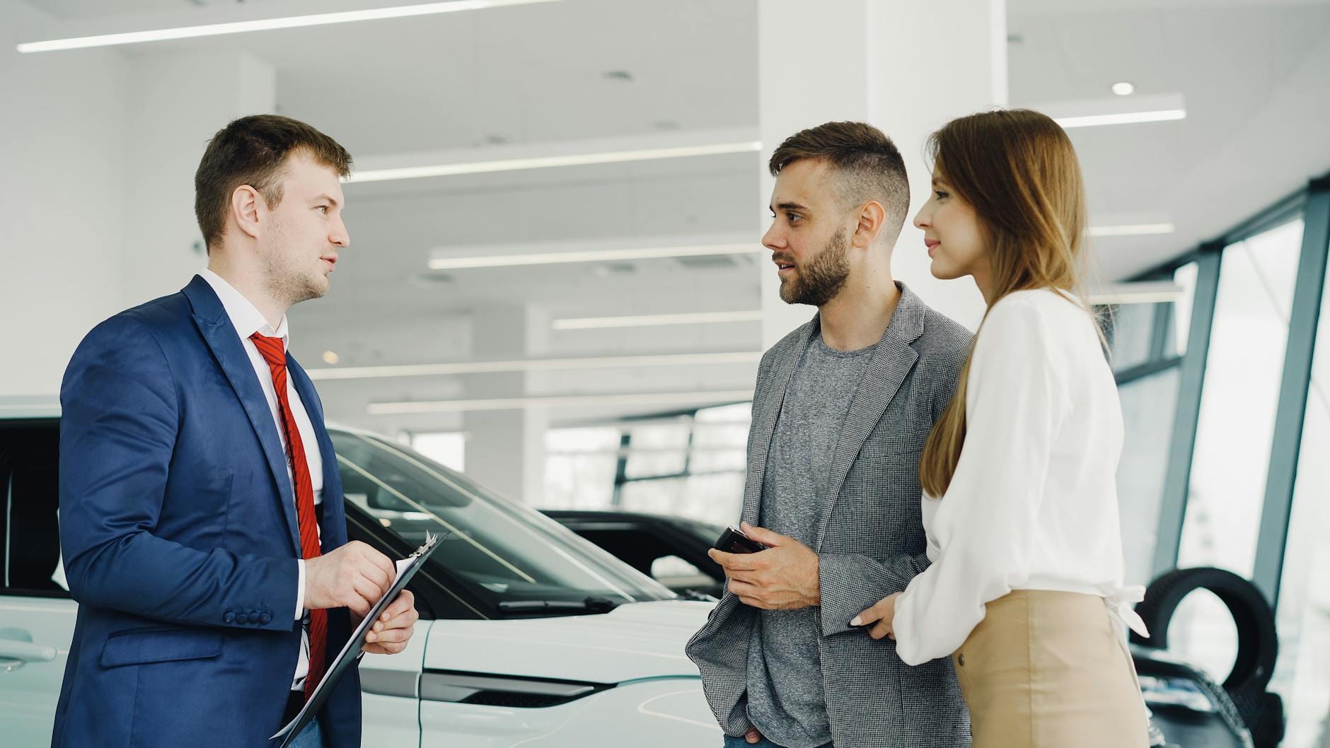 Jak bezpiecznie kupić auto używane w komisie: praktyczny poradnik krok po kroku Para ogląda luksusowe auto w salonie z pomocą sprzedawcy